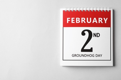 Photo of Top view of calendar with date February 2nd on light background, space for text. Groundhog day