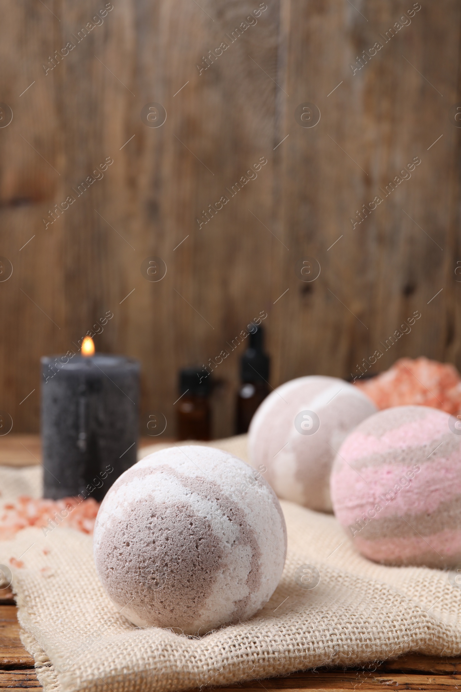 Photo of Bath bombs and burning candle on table, closeup. Space for text
