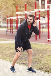 Young man with headphones taking break on sports ground