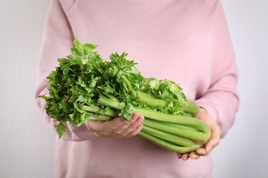 Photo of Woman holding fresh green celery on white background, closeup