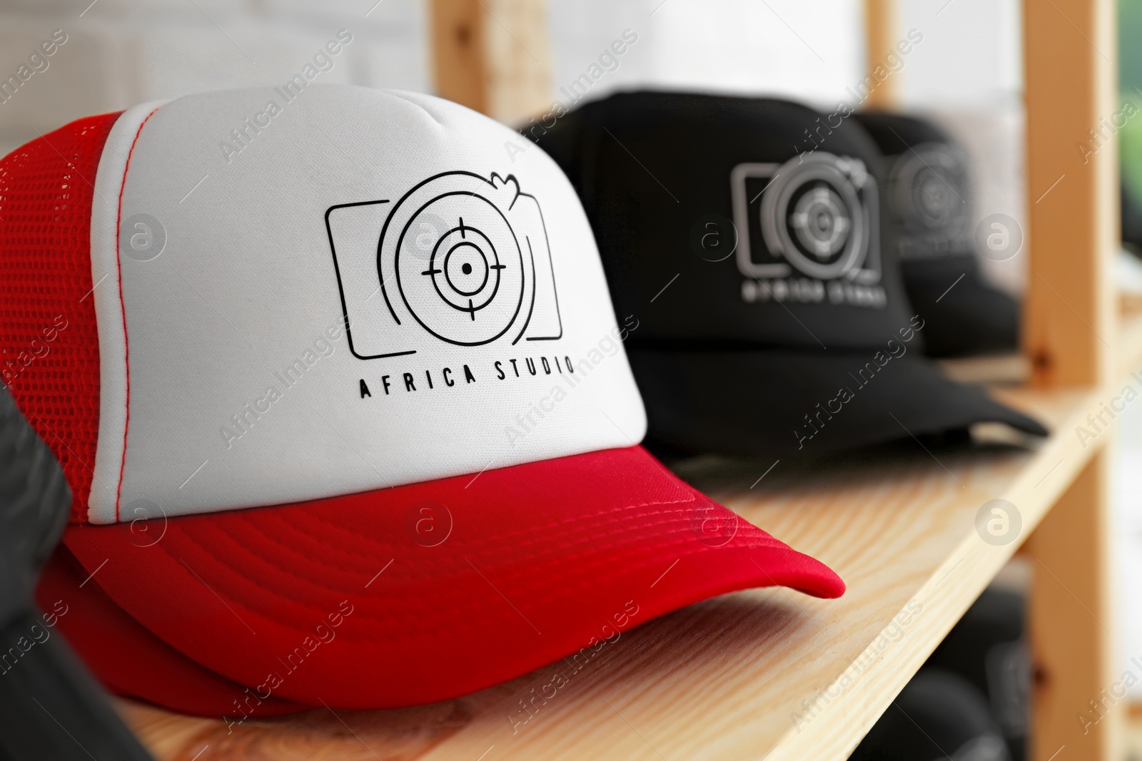 Photo of Caps with logo on wooden shelf in shop, closeup