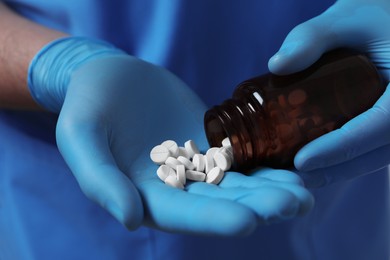 Doctor pouring pills from bottle, closeup view