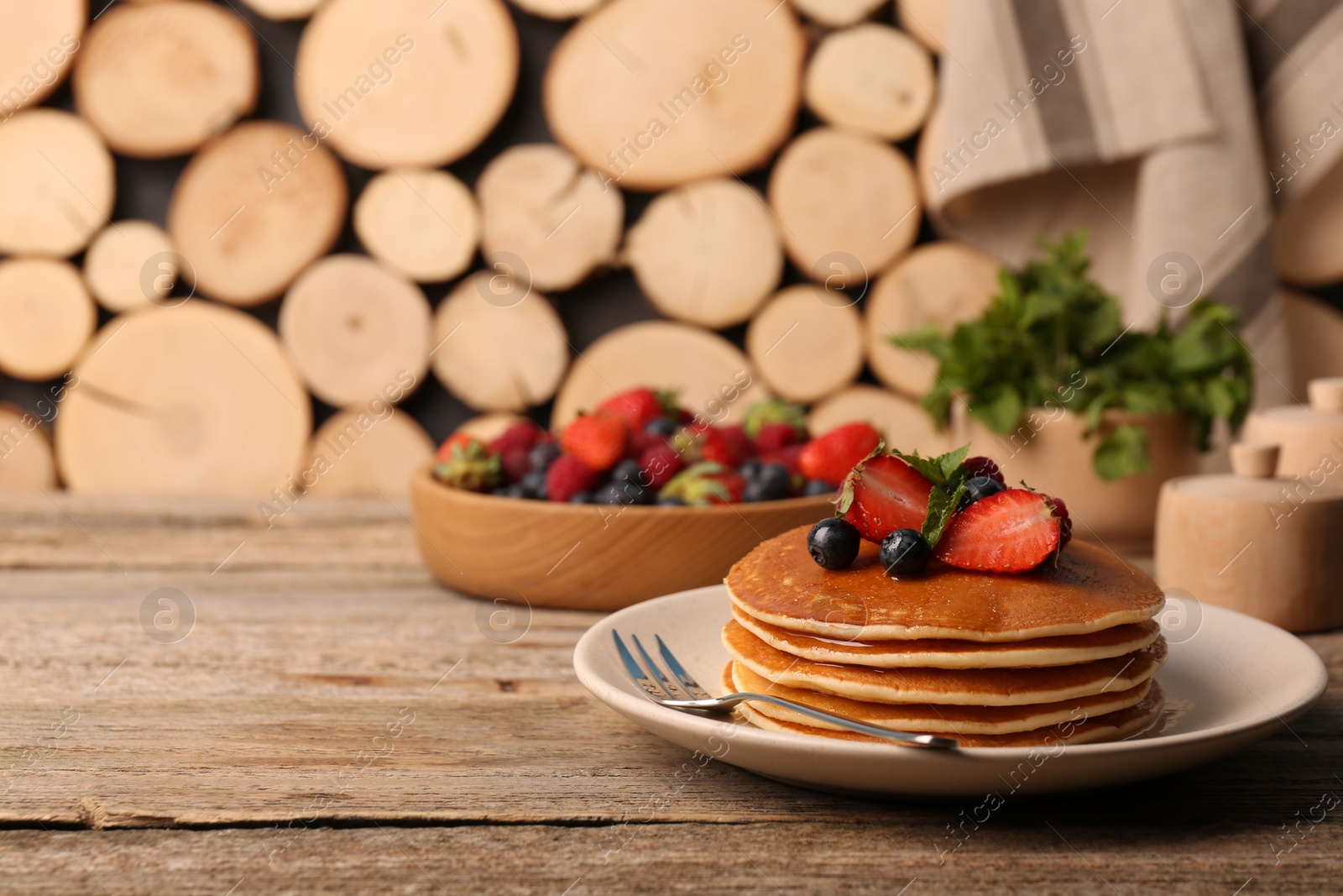 Photo of Stack of tasty pancakes with fresh berries and mint on wooden table. Space for text