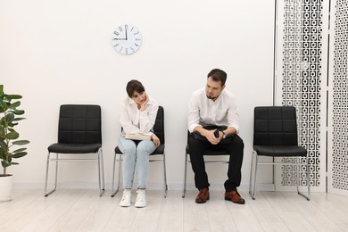 Man and woman waiting for job interview indoors