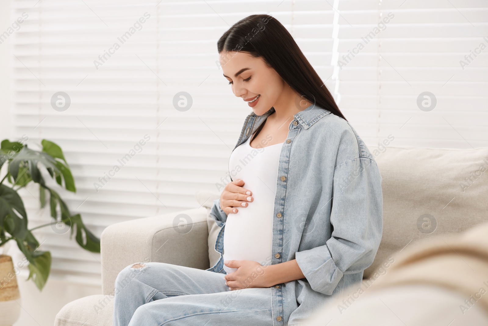 Photo of Happy pregnant woman on sofa at home