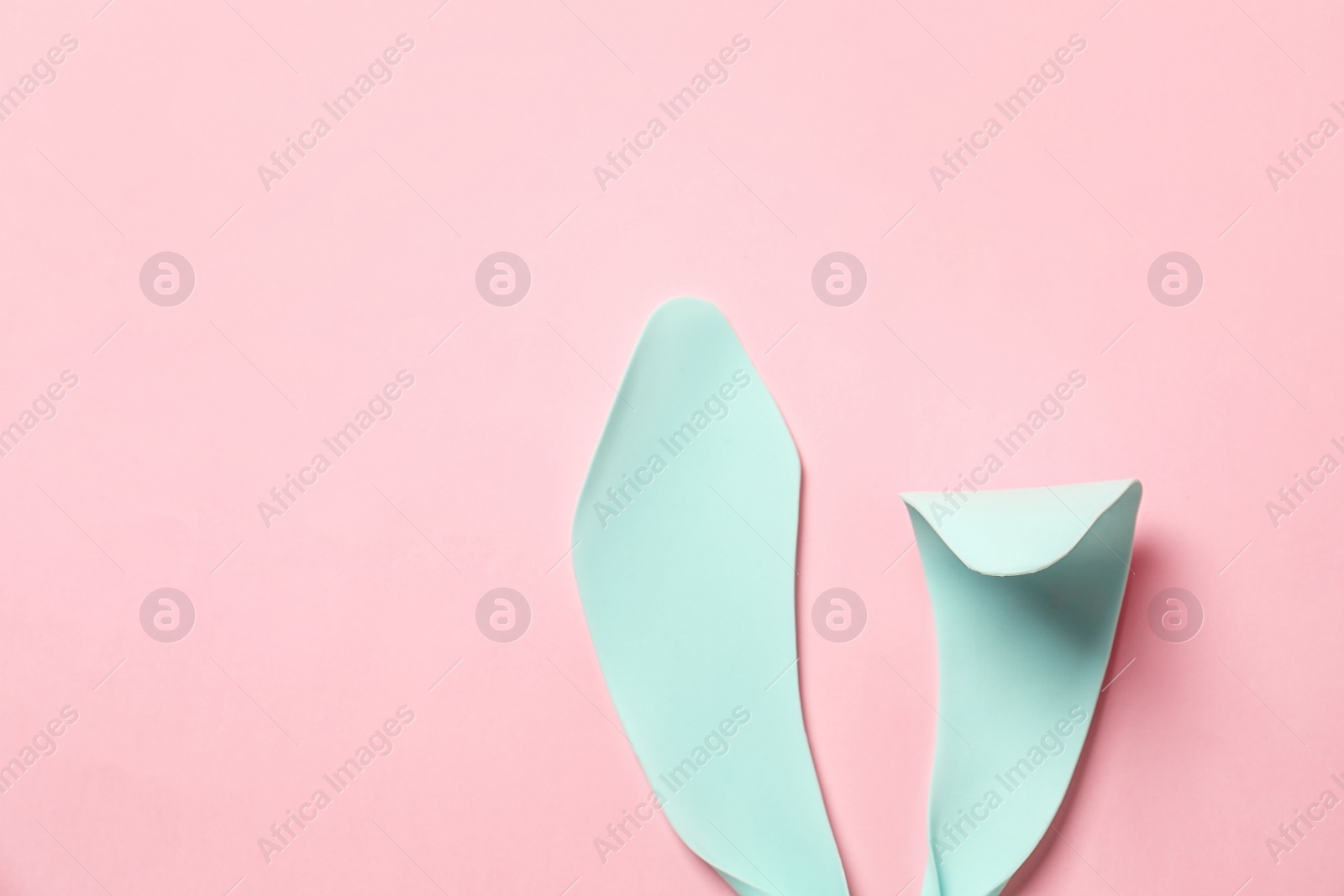 Photo of Funny Easter bunny ears on color background, top view with space for text