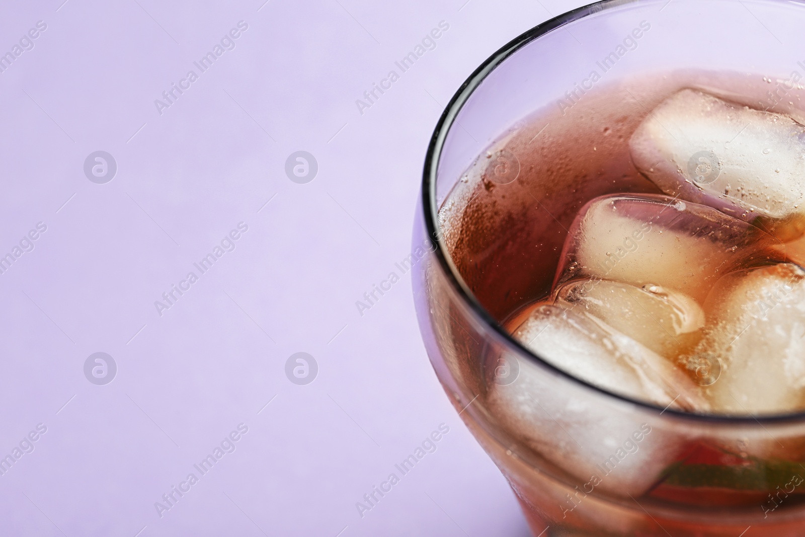 Photo of Glass of refreshing iced tea on lilac background, closeup. Space for text