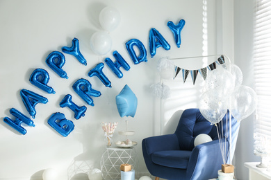 Photo of Phrase HAPPY BIRTHDAY made of blue balloon letters in decorated room