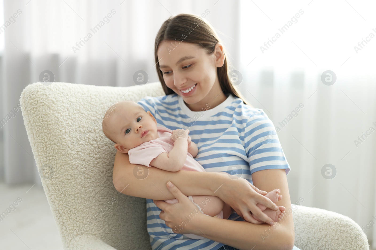 Photo of Mother with her cute baby in armchair at home