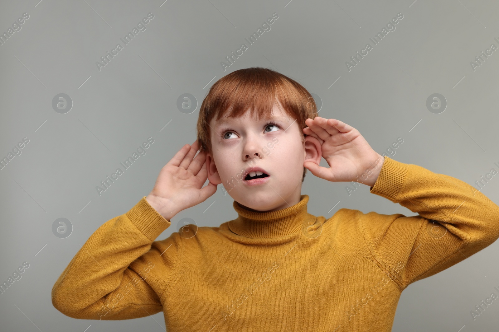 Photo of Little boy with hearing problem on grey background