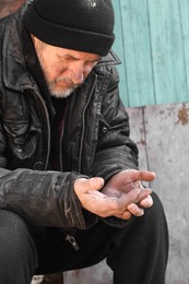 Photo of Poor homeless senior man holding coins outdoors