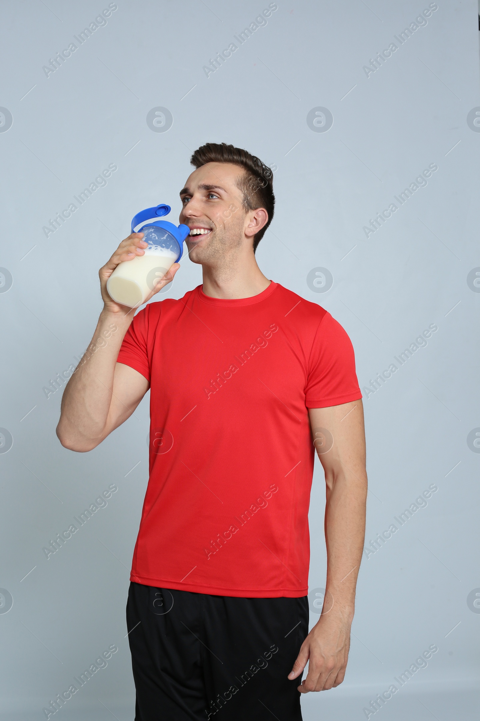 Photo of Portrait of man drinking protein shake on color background
