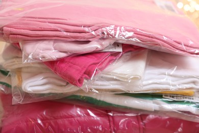 Photo of Stack of folded clothes in plastic bags, closeup