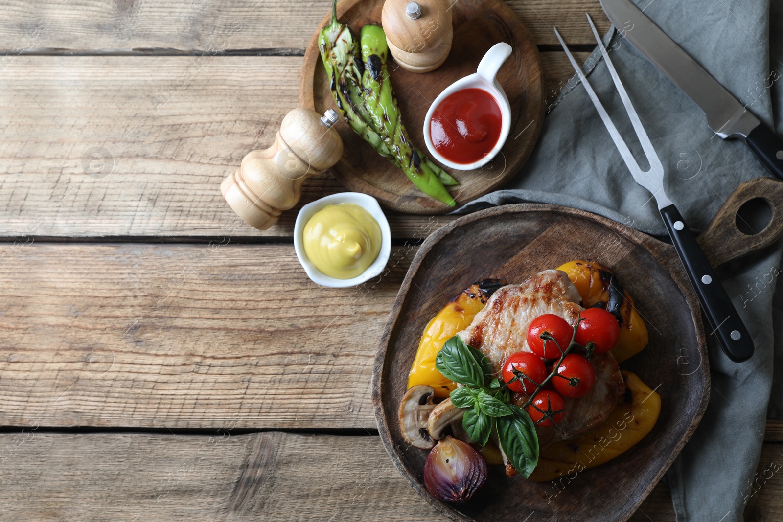 Photo of Delicious grilled meat and vegetables served with sauces on wooden table, flat lay. Space for text