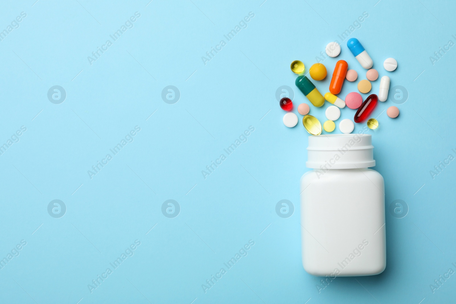Photo of Bottle and scattered pills on color background, top view. Space for text