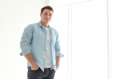 Photo of Portrait of confident young man near window, indoors