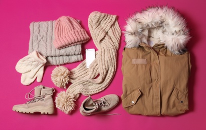 Flat lay composition with warm clothes for winter vacation on color background