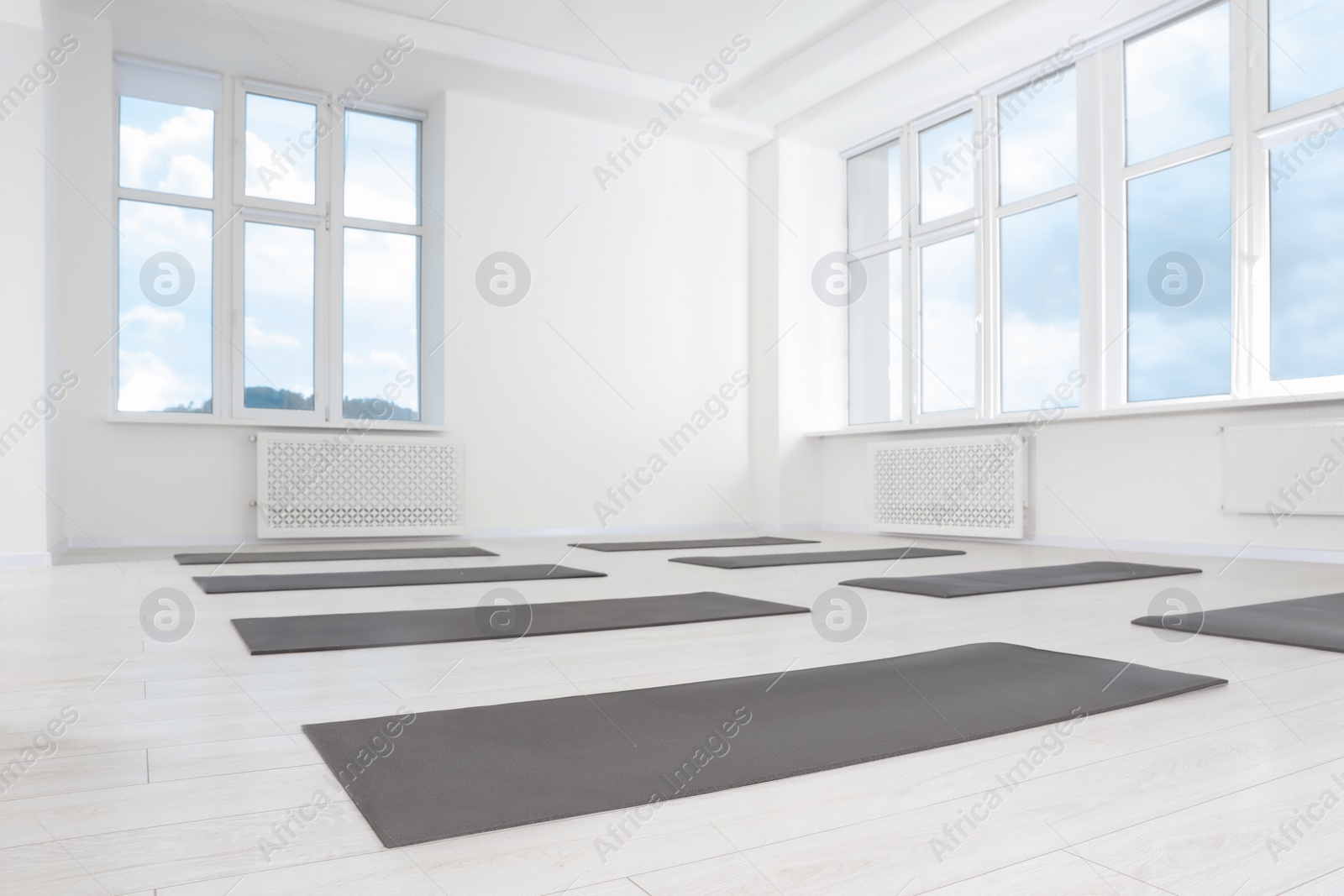 Photo of Spacious yoga studio with exercise mats and big windows, low angle view