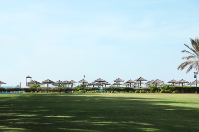 Photo of Beautiful landscape with beach umbrellas at tropical resort on sunny day