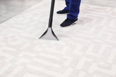 Photo of Man removing dirt from carpet with vacuum cleaner indoors, closeup. Space for text