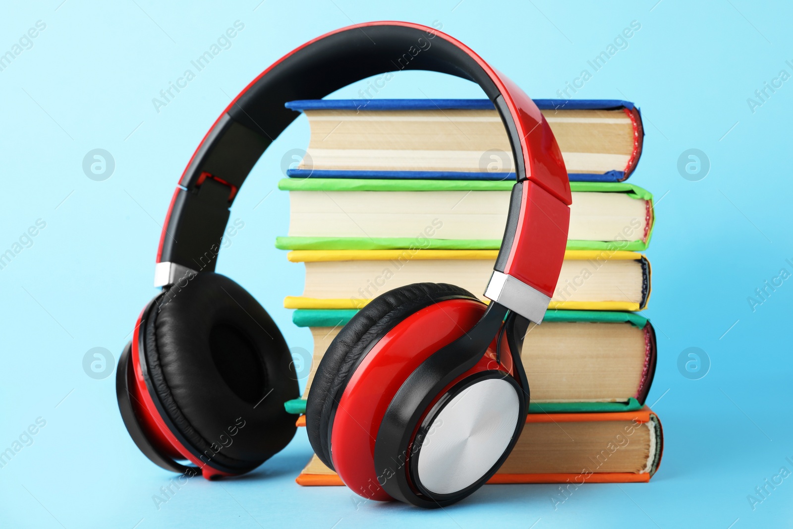 Photo of Books and modern headphones on light blue background