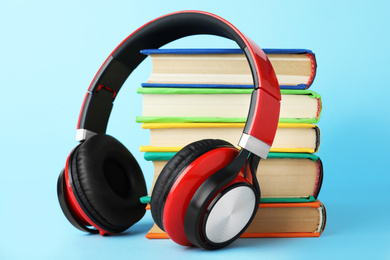 Books and modern headphones on light blue background