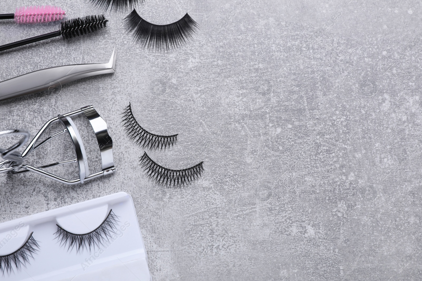 Photo of Flat lay composition with false eyelashes and tools on light grey background. Space for text