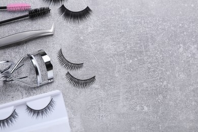 Flat lay composition with false eyelashes and tools on light grey background. Space for text