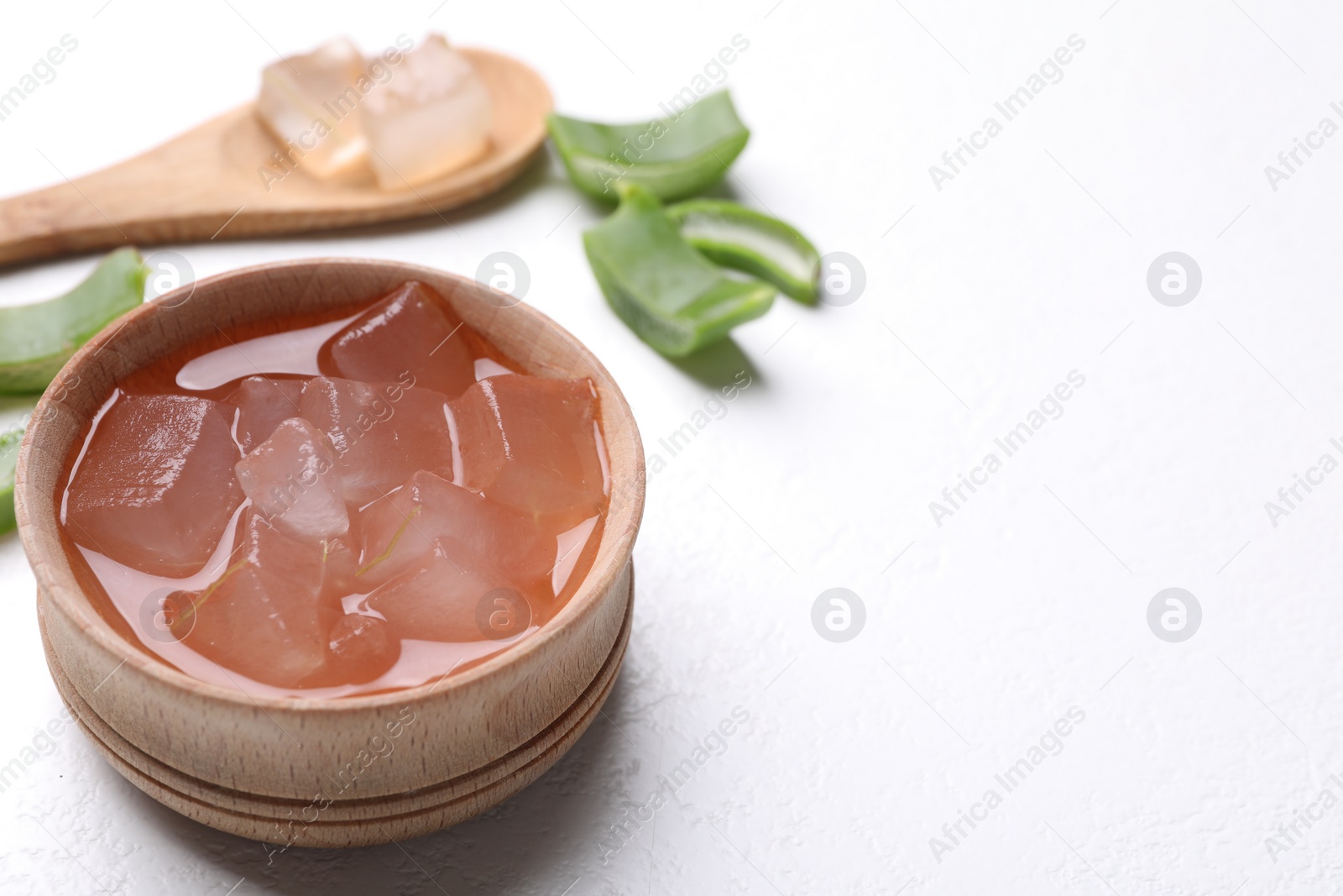 Photo of Aloe vera gel and slices of plant on white background, closeup. Space for text