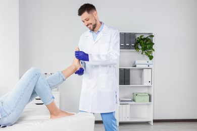 Male orthopedist fitting insole to patient's foot in hospital