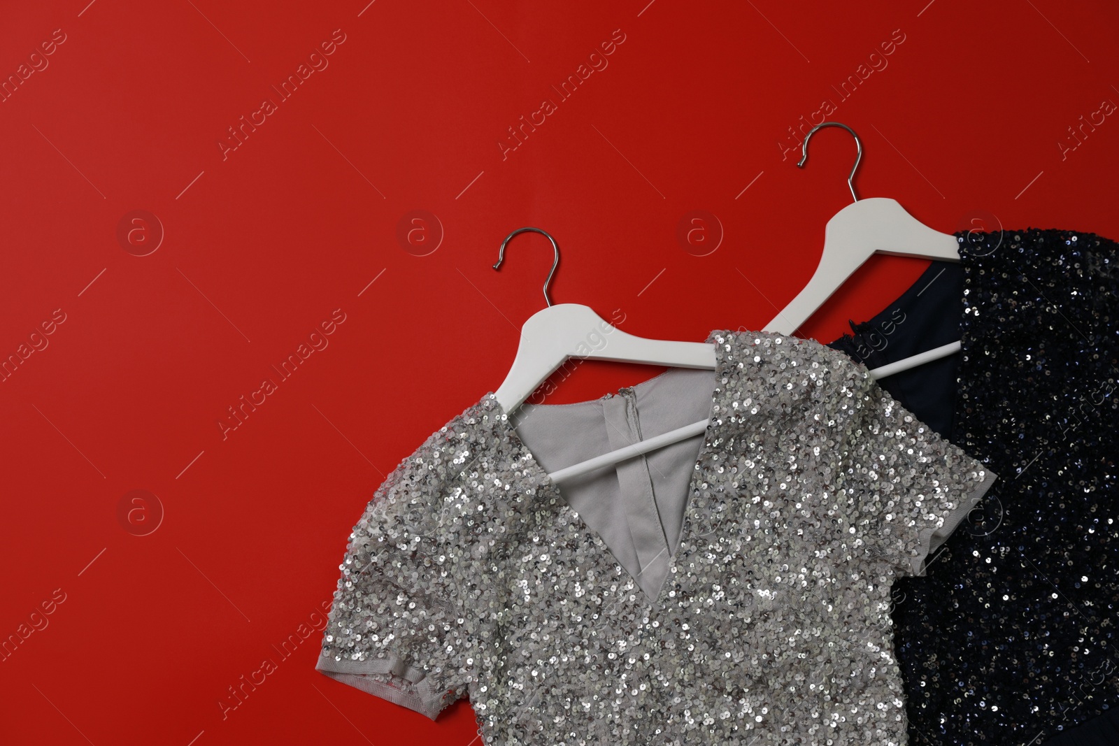 Photo of Beautiful dresses on red background, flat lay with space for text. Rental clothing service