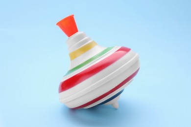 Photo of One bright spinning top on light blue background. Toy whirligig