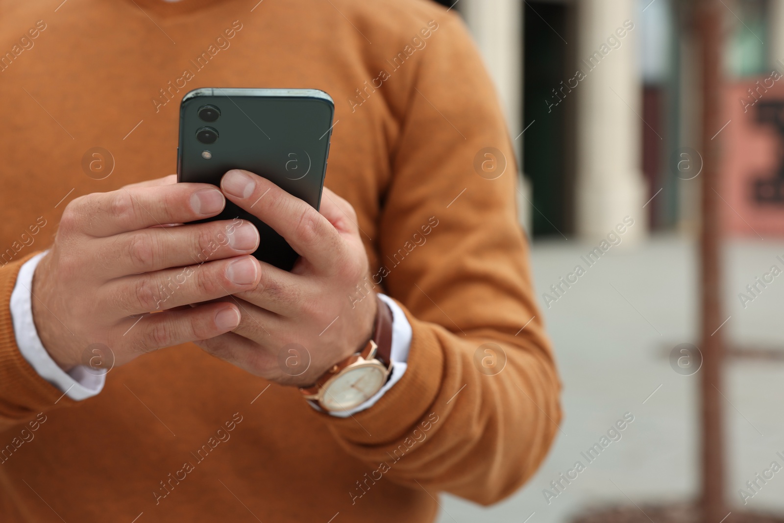 Photo of Man with smartphone on city street, closeup. Space for text