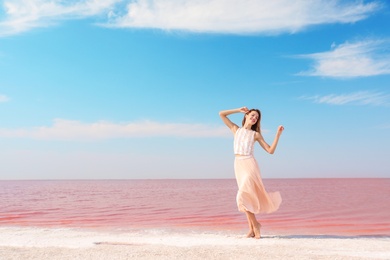 Beautiful woman posing near pink lake on sunny day