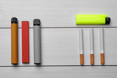 Photo of Lighter, electronic and regular cigarettes on white wooden background, flat lay. Space for text