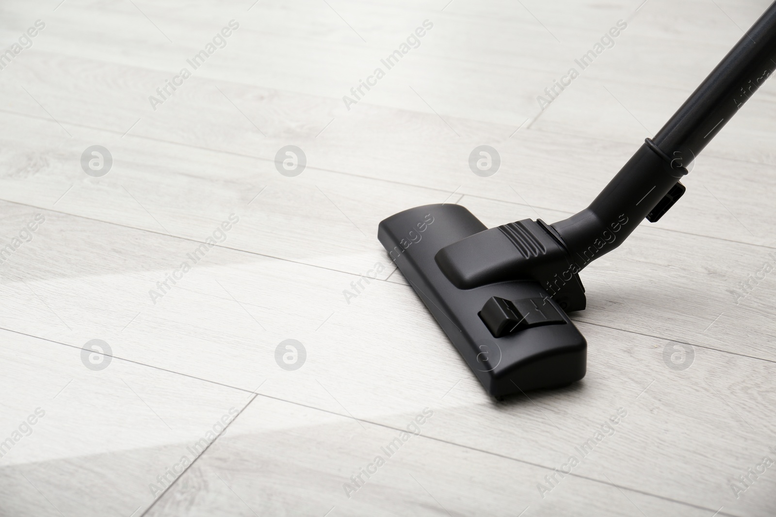 Image of Vacuuming white wooden floor. Clean area after using device, closeup