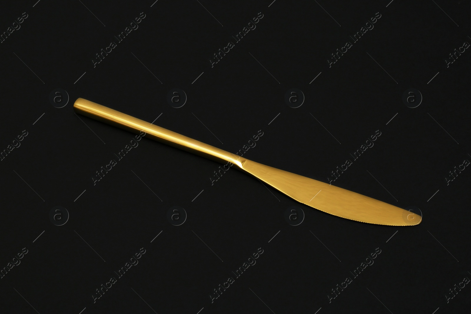 Photo of Shiny elegant gold knife on black background