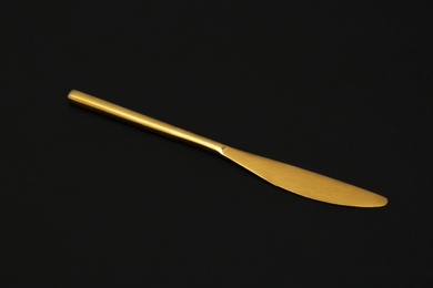 Shiny elegant gold knife on black background