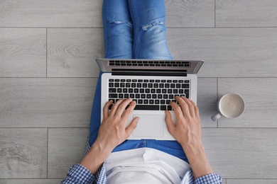 Young man using laptop while sitting on floor, top view