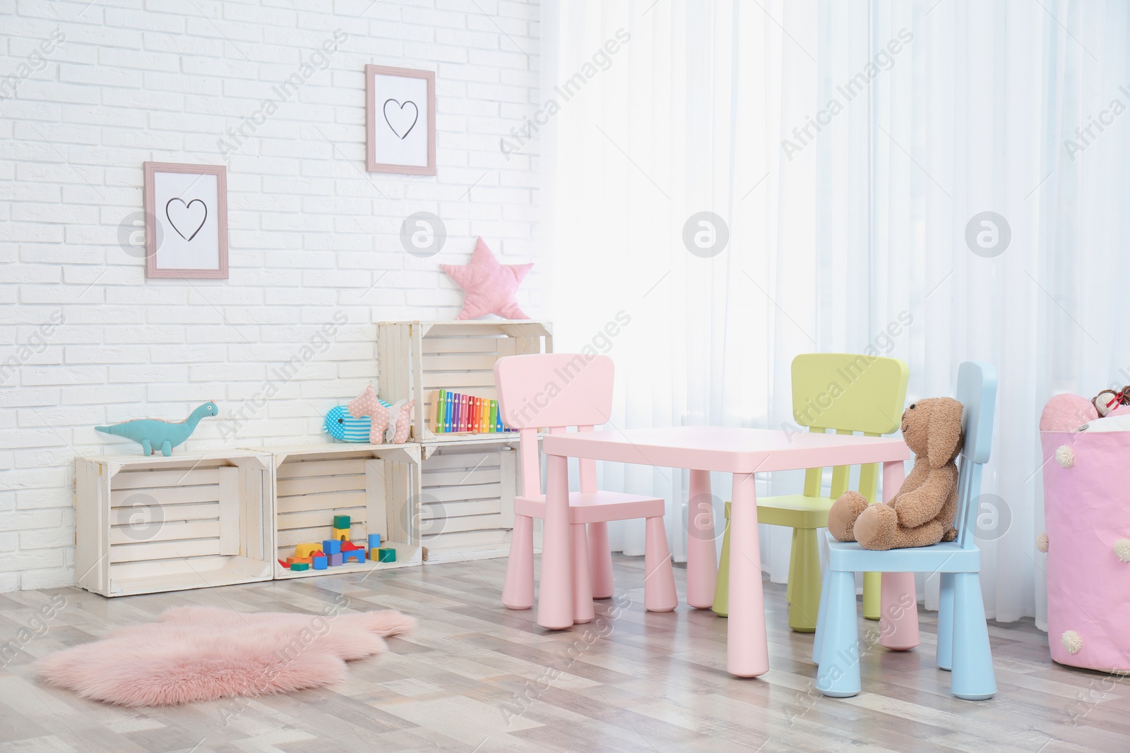 Photo of Cozy kids room interior with table, chairs and toys