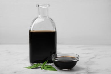 Photo of Organic balsamic vinegar and basil on white marble table