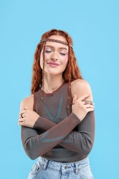 Beautiful young hippie woman on light blue background