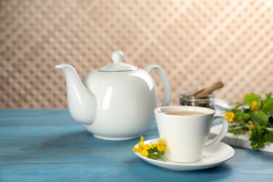 Photo of Aromatic celandine tea and flowers on light blue wooden table