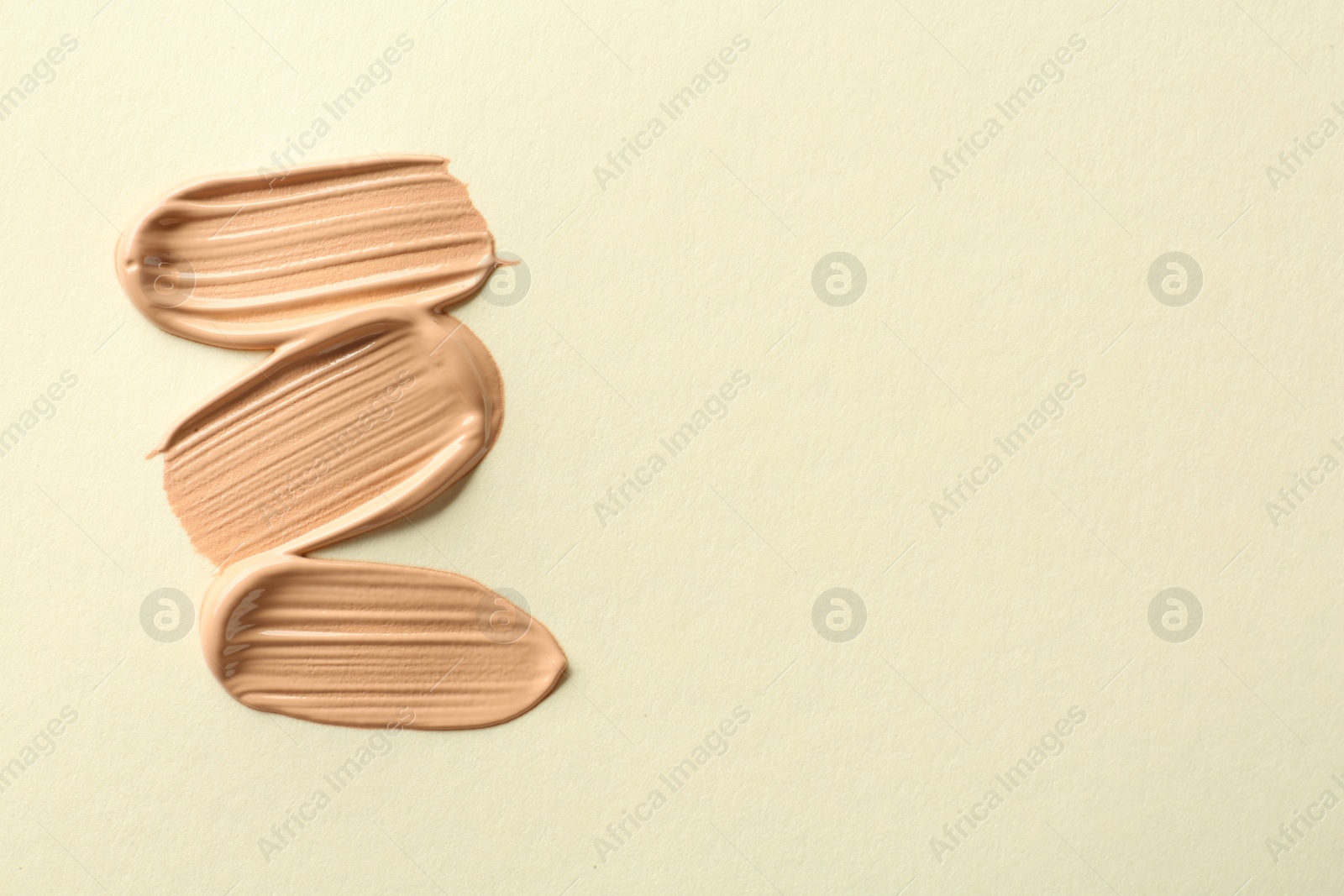 Photo of Samples of liquid skin foundations on beige background, top view. Space for text