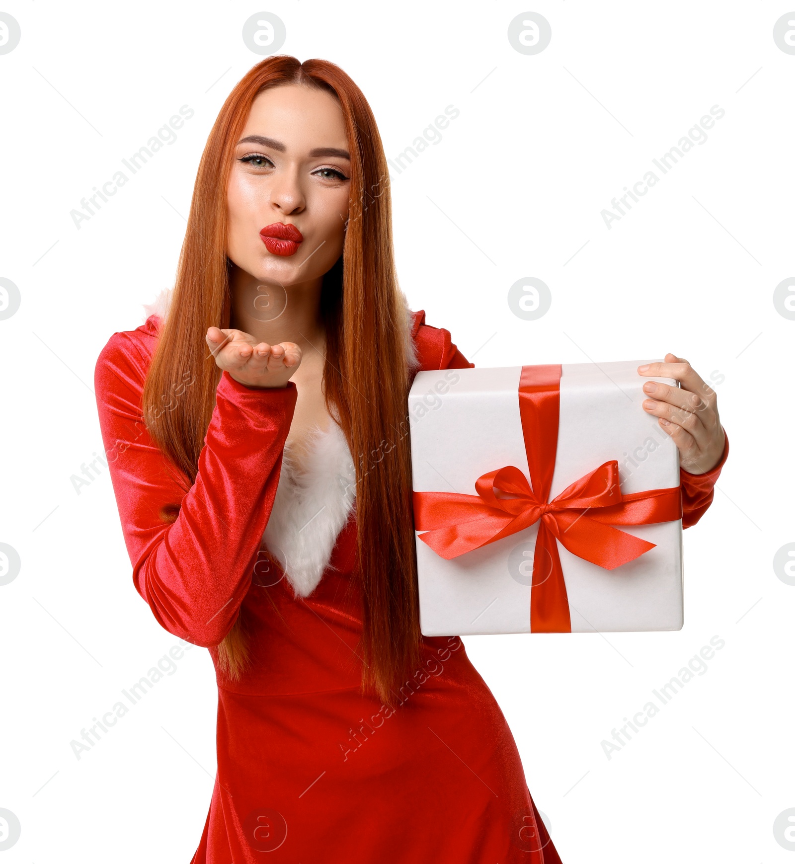 Photo of Young woman in red dress with Christmas gift blowing kiss on white background