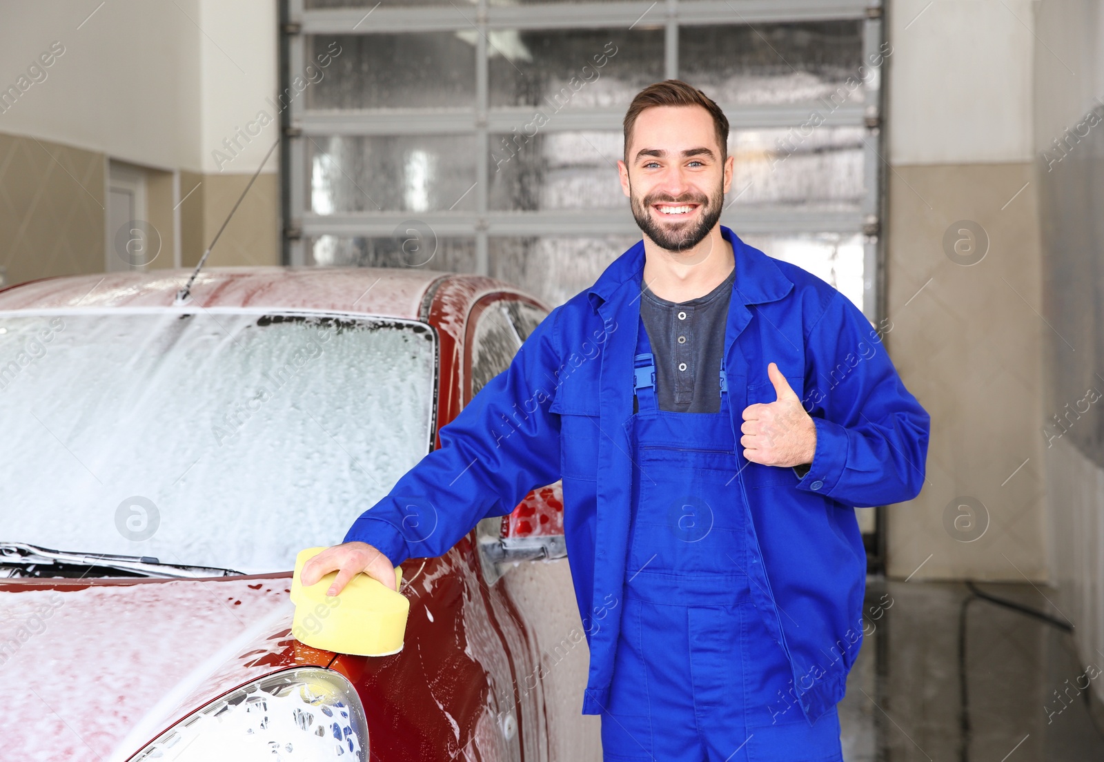 Photo of Portrait of worker with sponge near auto at car wash