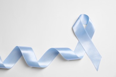 Photo of International Psoriasis Day. Light blue ribbon as symbol of support on white background, top view