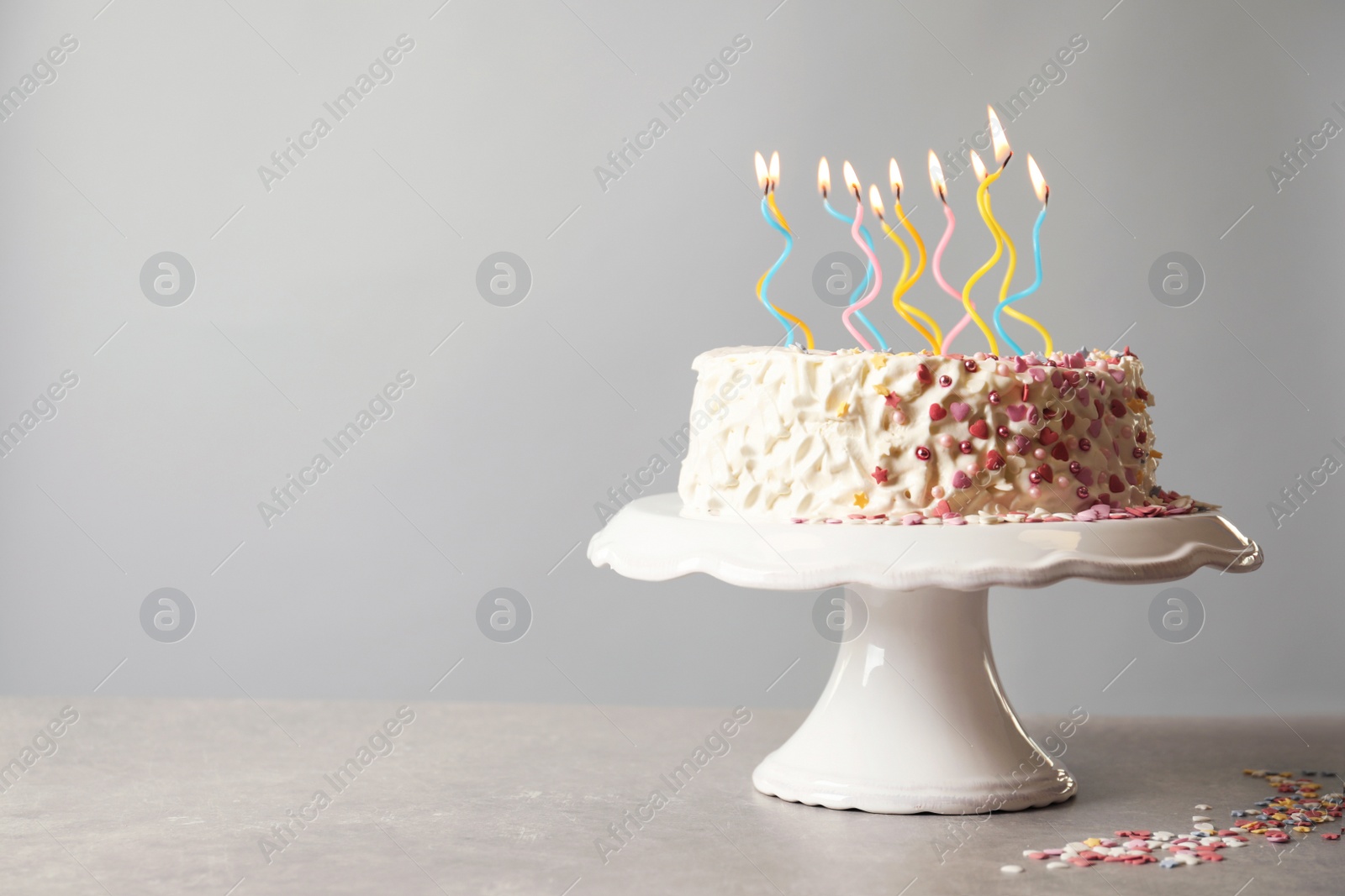 Photo of Birthday cake with candles on table against gray background