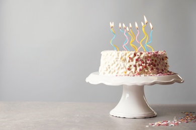 Photo of Birthday cake with candles on table against gray background