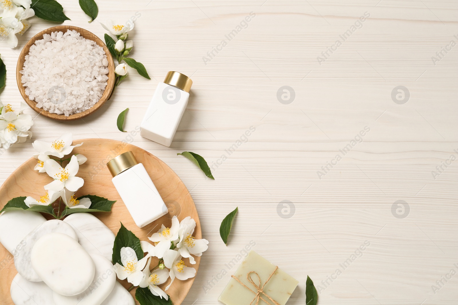 Photo of Flat lay composition with spa stones and beautiful jasmine flowers on white wooden table, space for text